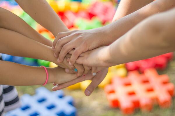 Bild vergrößern: Bild vergrößern: Zusammengelegte Hände von Kindern und Jugendlichen zur Vermittlung des Zusammengehörigkeitsgefühls