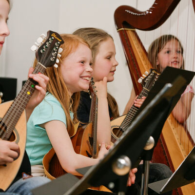 Bild vergrößern: Kinder im Musikunterricht mit Ukulele und Harfe
