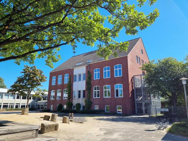 Bild vergrößern: Außenansicht des Gebäudes der Helene-Lange-Schule mit Schulhof im Vordergrund